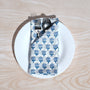 Single blue floral napkin wrapped around silverware on a white plate.

