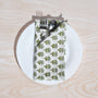 Single green floral napkin folded under silverware on a white plate