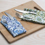 Blue floral napkin folded with silverware on a wooden serving tray.

