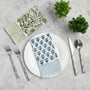 Single blue floral napkin folded under silverware on a white plate.

