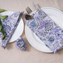 Single blue floral napkin folded under silverware on a white plate.