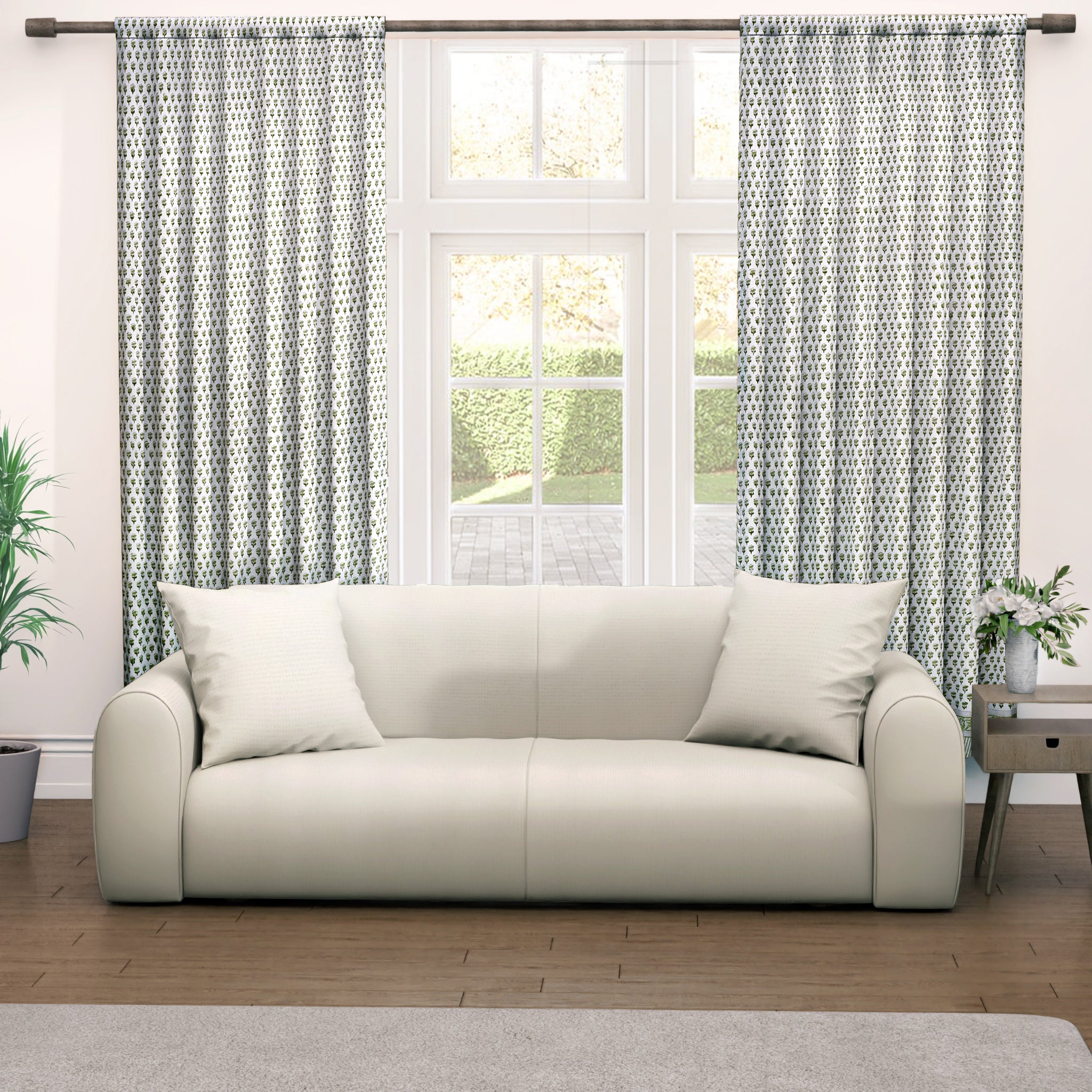 Semi-sheer cotton block print curtains in emerald green, hanging on a rod pocket, allowing natural light to filter through, with a patterned design, placed in a room with a chair and a plant.
