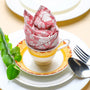 Rolled pink floral napkin placed upright on a plate, styled with green leaves and silverware.