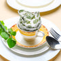 Rolled green floral napkin placed upright on a plate, styled with green leaves and silverware.
