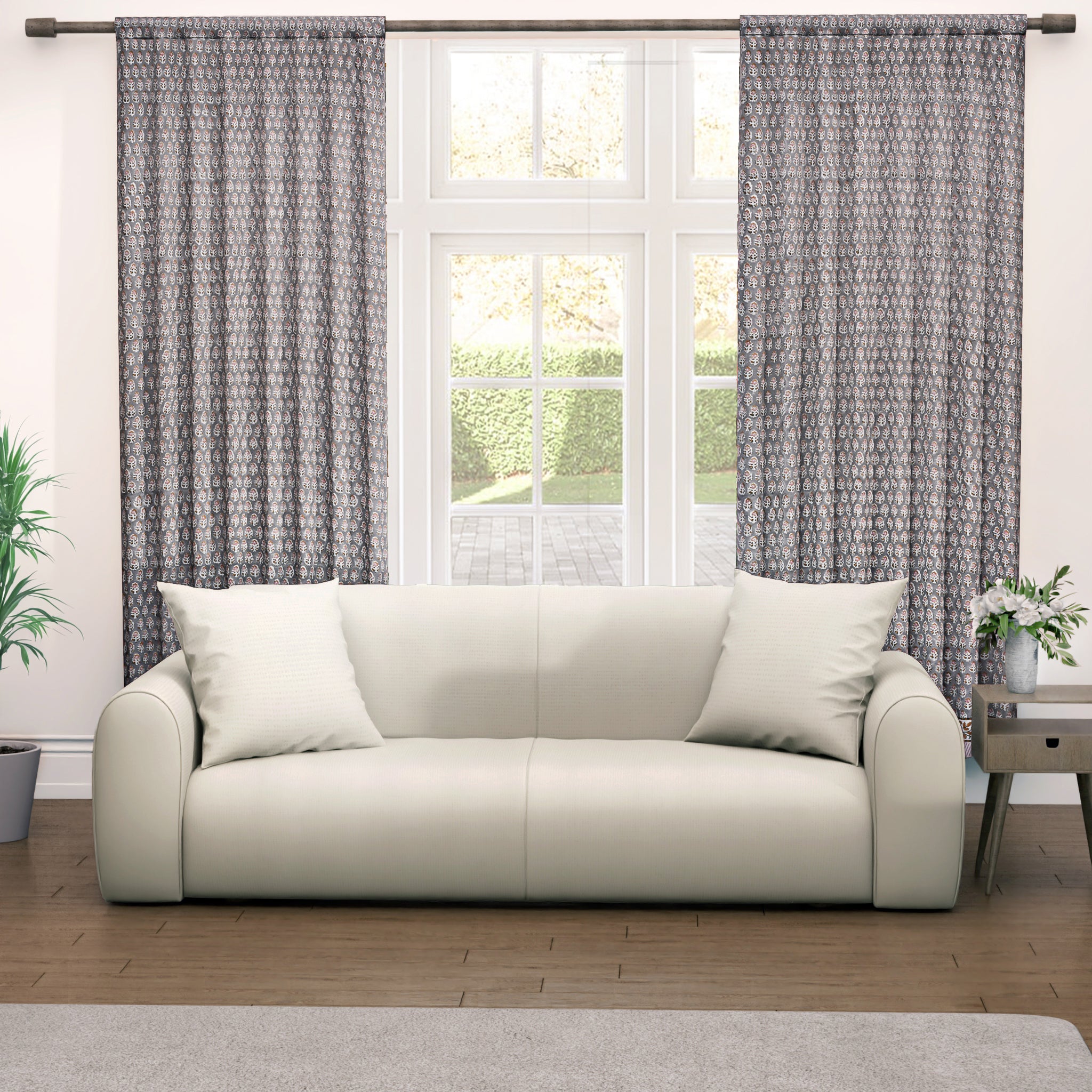 Semi-sheer cotton block print curtains in gray with intricate patterns, hanging in a room with a light source behind them, showcasing their transparent quality and rod pocket design.