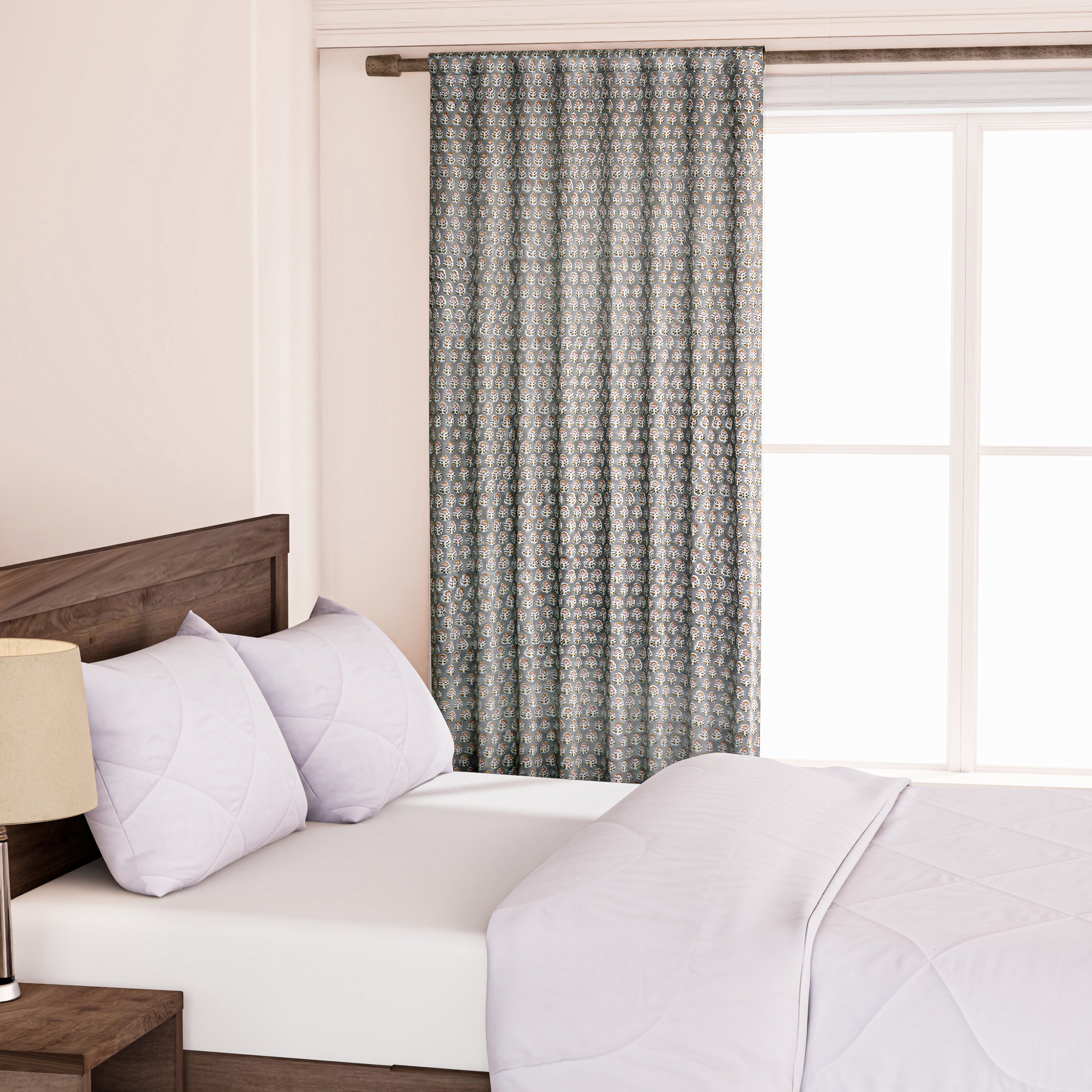 Semi-sheer cotton block print curtains in gray with intricate patterns, hanging in a room with a light source behind them, showcasing their transparent quality and rod pocket design.