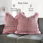 Pair of pink floral block print pillows with ruffled trim arranged neatly on a cream couch