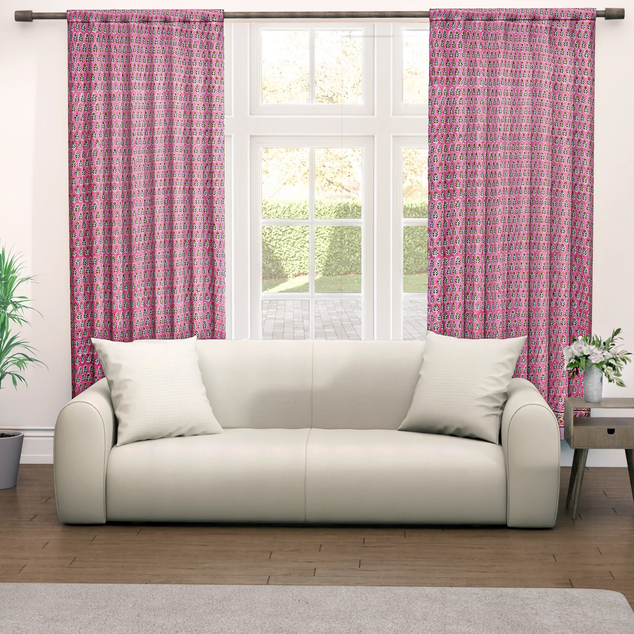 Semi-sheer cotton block print curtains in poppy pink with intricate patterns, hanging in a room with a light filtering through.