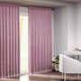 Semi-sheer cotton block print curtains in poppy pink with intricate patterns, hanging in a room with a light filtering through.