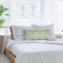 A decorative pillowcase with a floral pattern and ruffle trim, in shades of green and white, displayed on a bed.