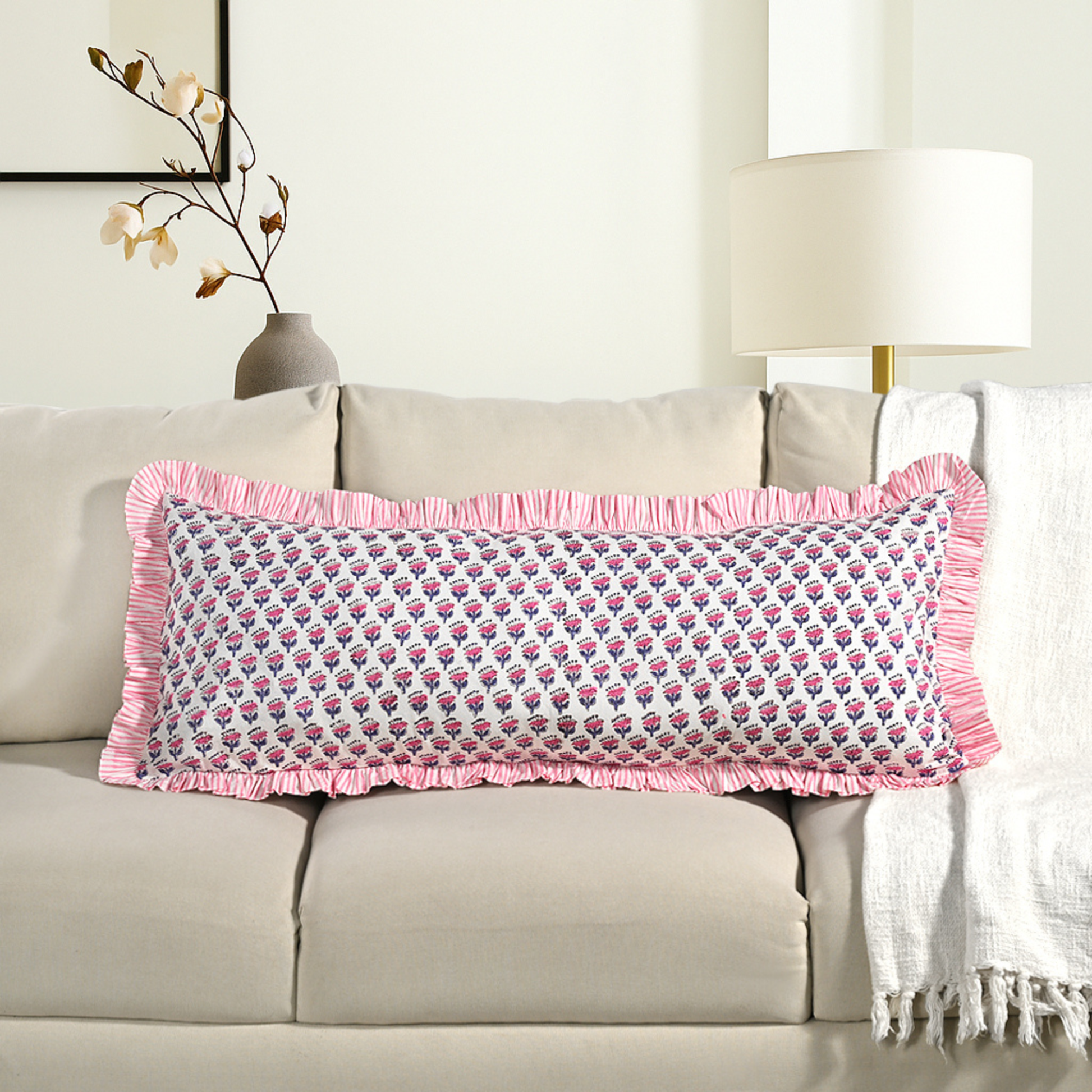 Pink block print bolster pillow on beige sofa with ruffle trim